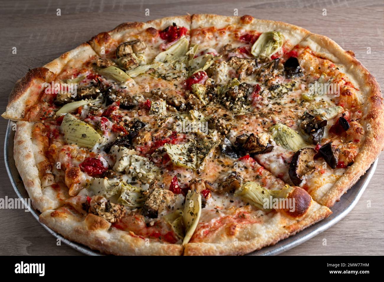 Gourmet pizza with artichoke, sun-dried tomato, eggplant, tomato sauce, on thin crust Stock Photo