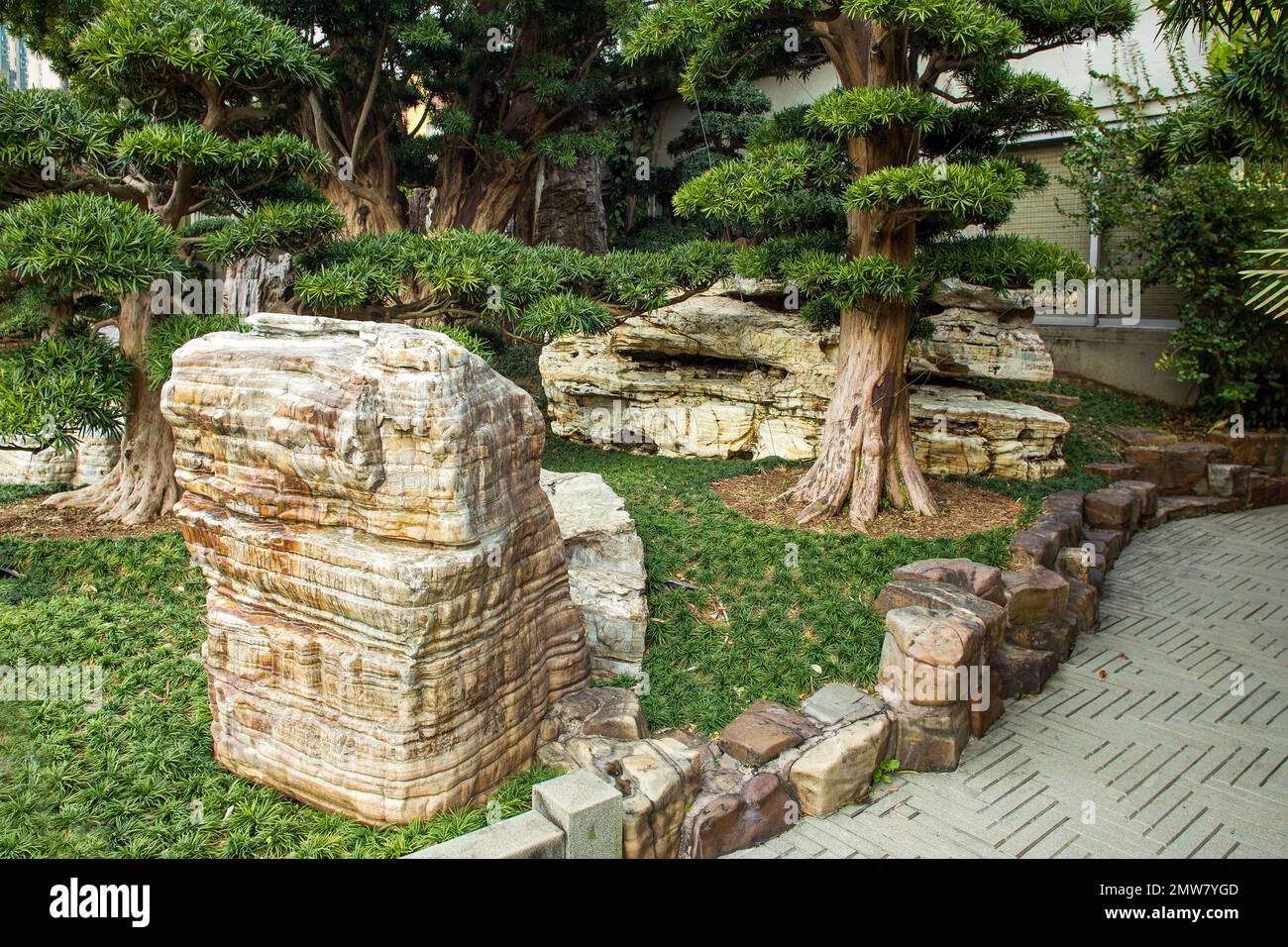 Superb View of the rocks (Taihu stone)  in Nan Lian Park with idyllic topiary podocarpus and pine trees and ophiopogon japonicus as grass in Chinese p Stock Photo