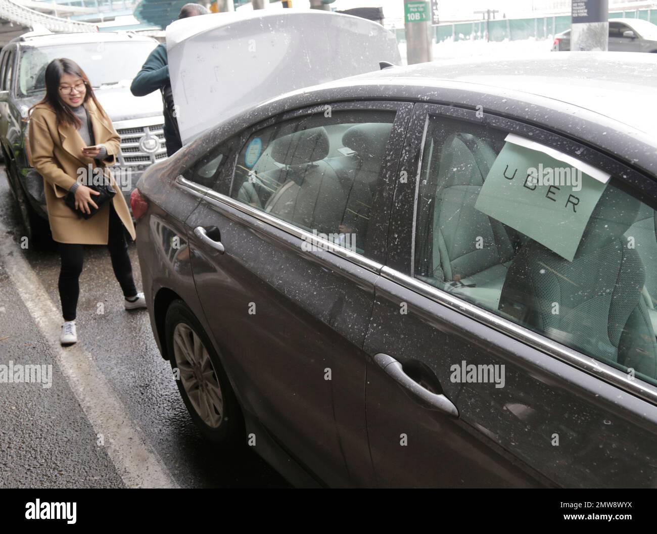 A woman puts her luggage in an Uber car at LaGuardia Airport in New