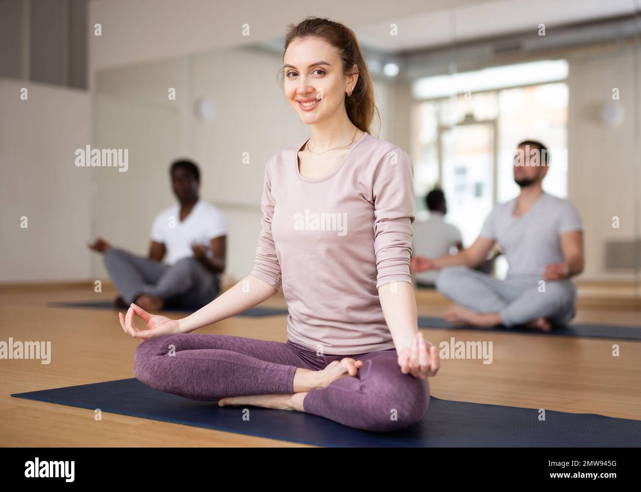 Woman sitting in lotus position with hands on knees folded in mudra ...