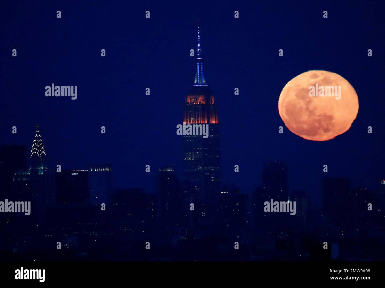 The full moon rises behind the New York City skyline, including the ...