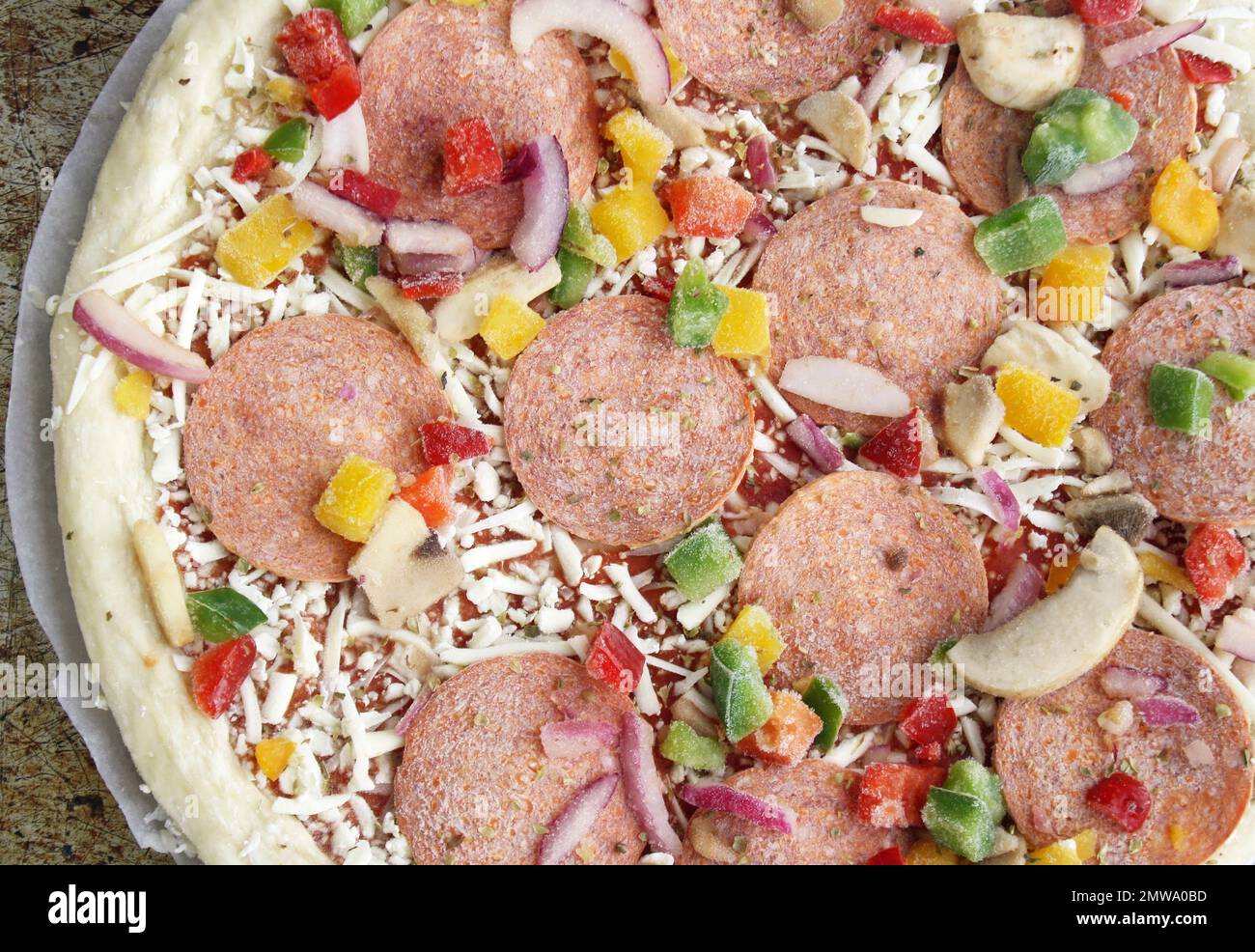 Frozen pizza before cooking. Toppings include pepperoni, diced red