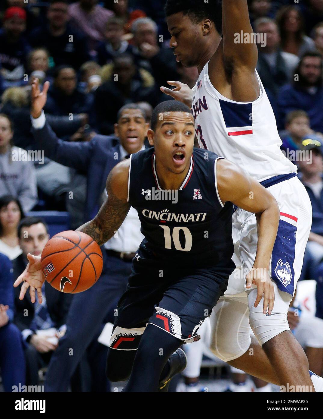 Cincinnati's Troy Caupain (10) drives past Connecticut's Steven Enoch ...