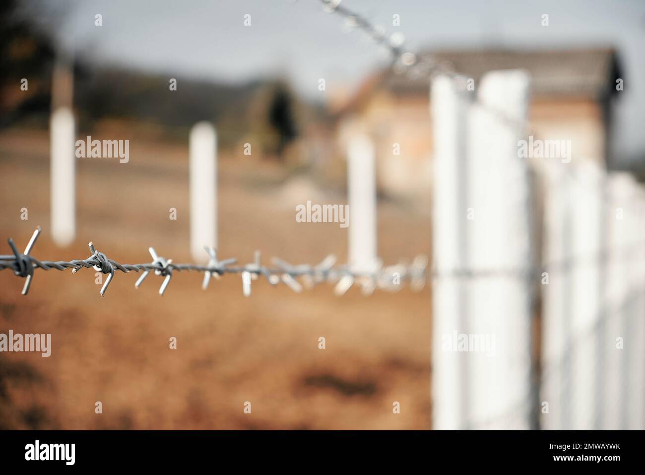 Barbwire on fence around a private property, selective focus closeup Stock Photo