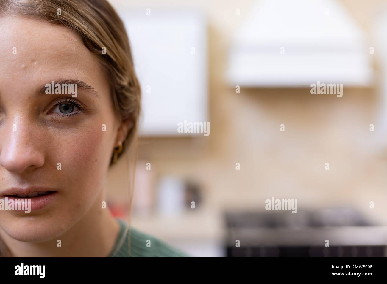 Half face portrait of thoughtful blonde caucasian woman in kitchen at home, copy space Stock Photo