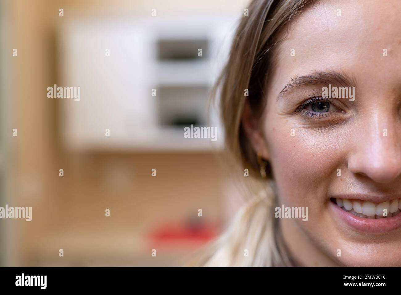 Half face portrait of smiling blonde caucasian woman in kitchen at home, copy space Stock Photo