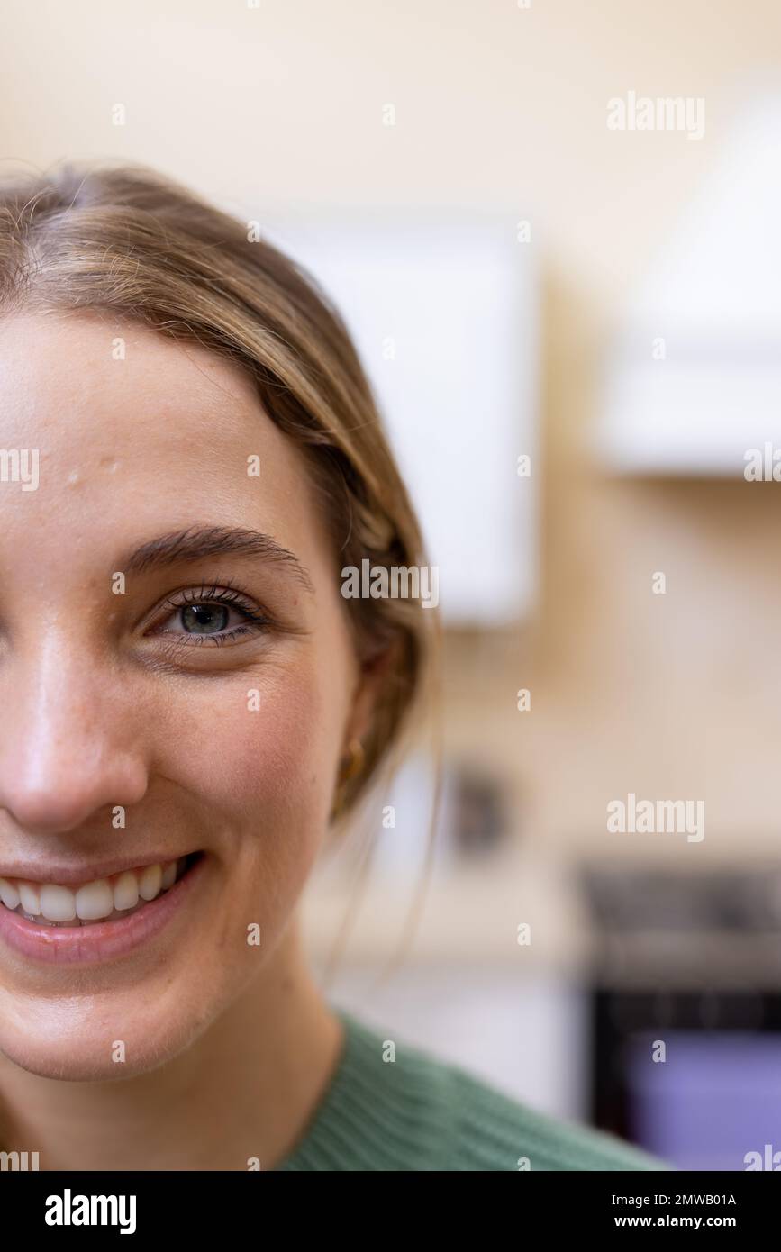 Vertical half face portrait of smiling blonde caucasian woman in kitchen at home, copy space Stock Photo
