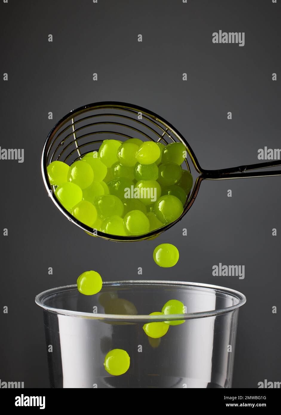 green jelly bubble tea balls and plastic cup on dark black background