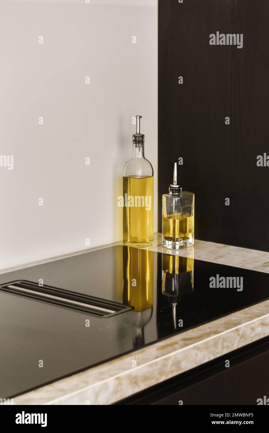 a black and white kitchen counter with a bottle of olive oil on the countertop, next to it is a