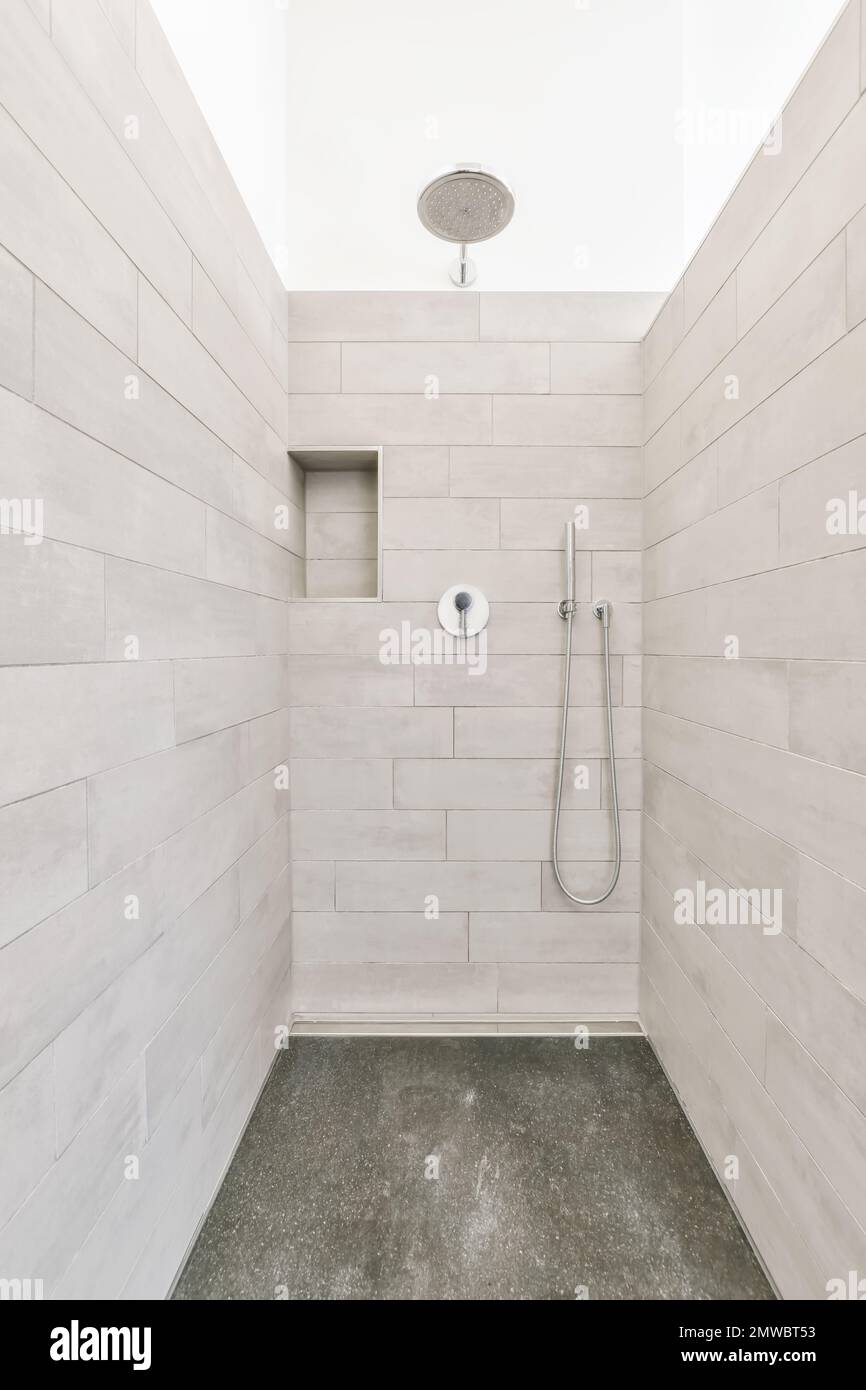 a walk in shower with gray tile flooring and white wall tiles on the