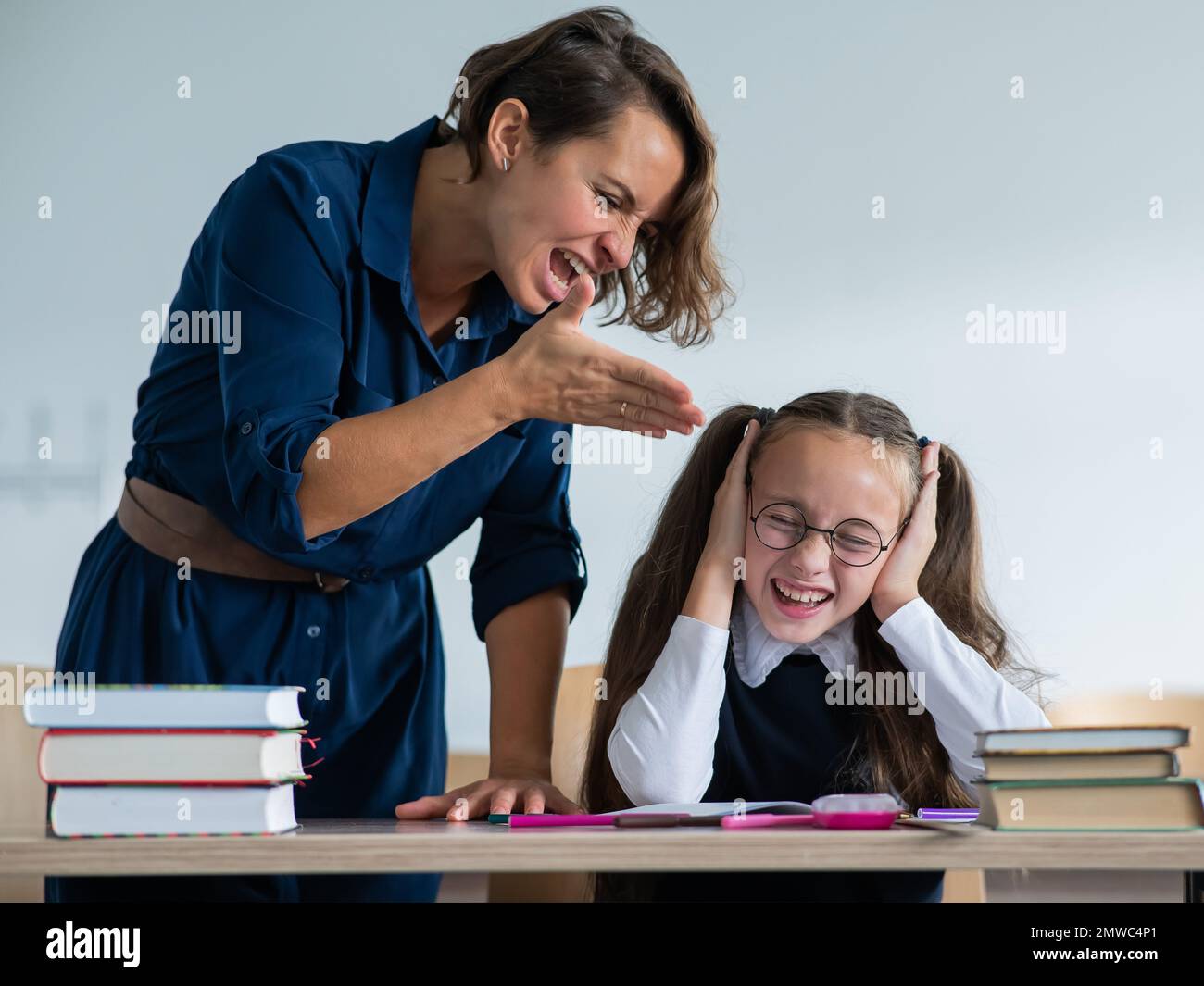 A female teacher yells at a student. Little girl covers her ears with