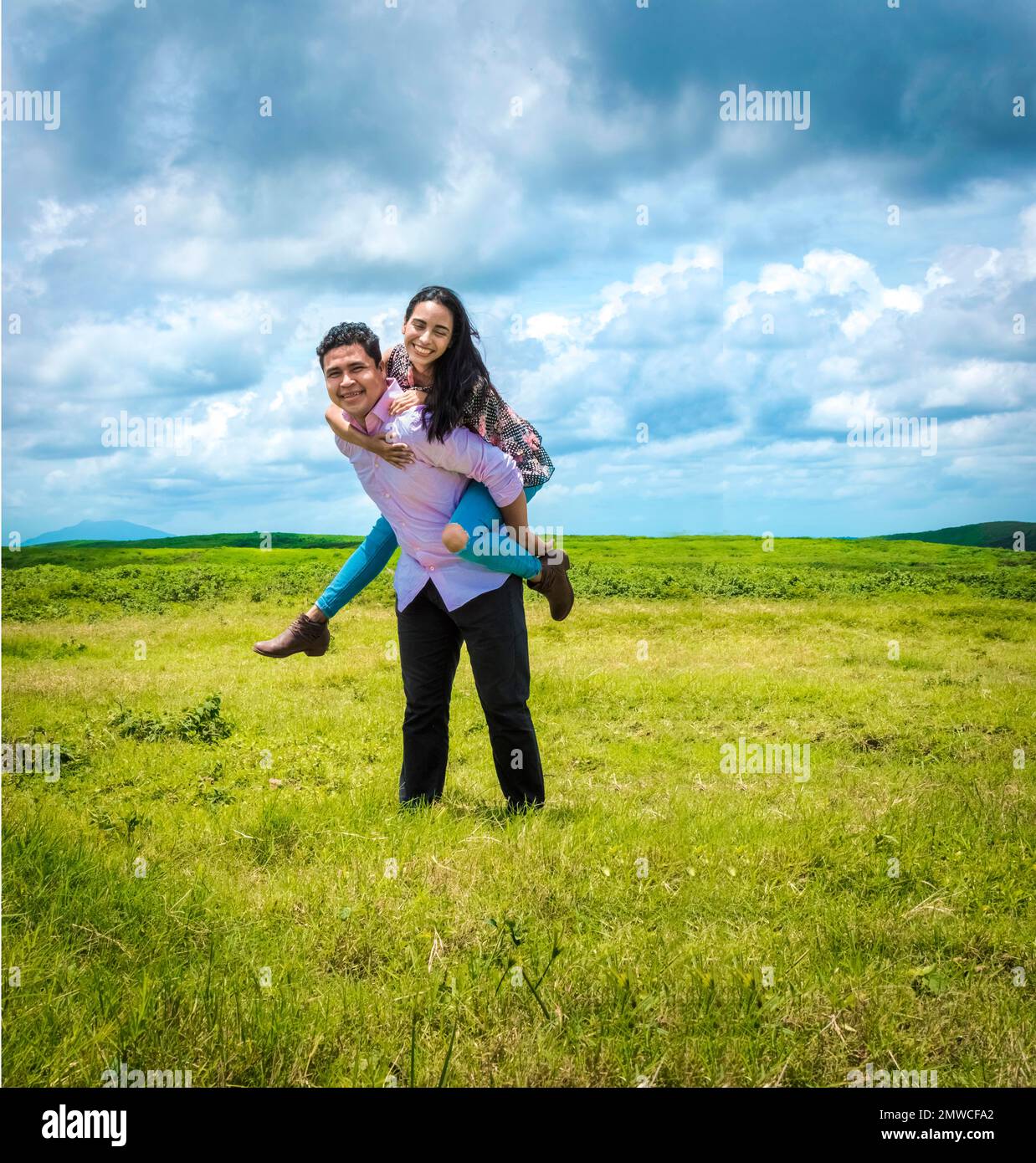Happy couple in love in the field, happy man carrying his girlfriend in
