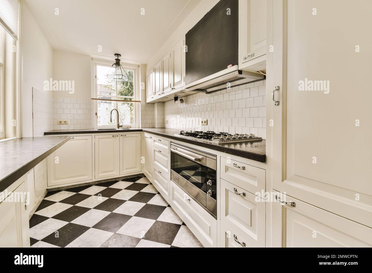 a kitchen with black and white checkered tiles on the floor, along with