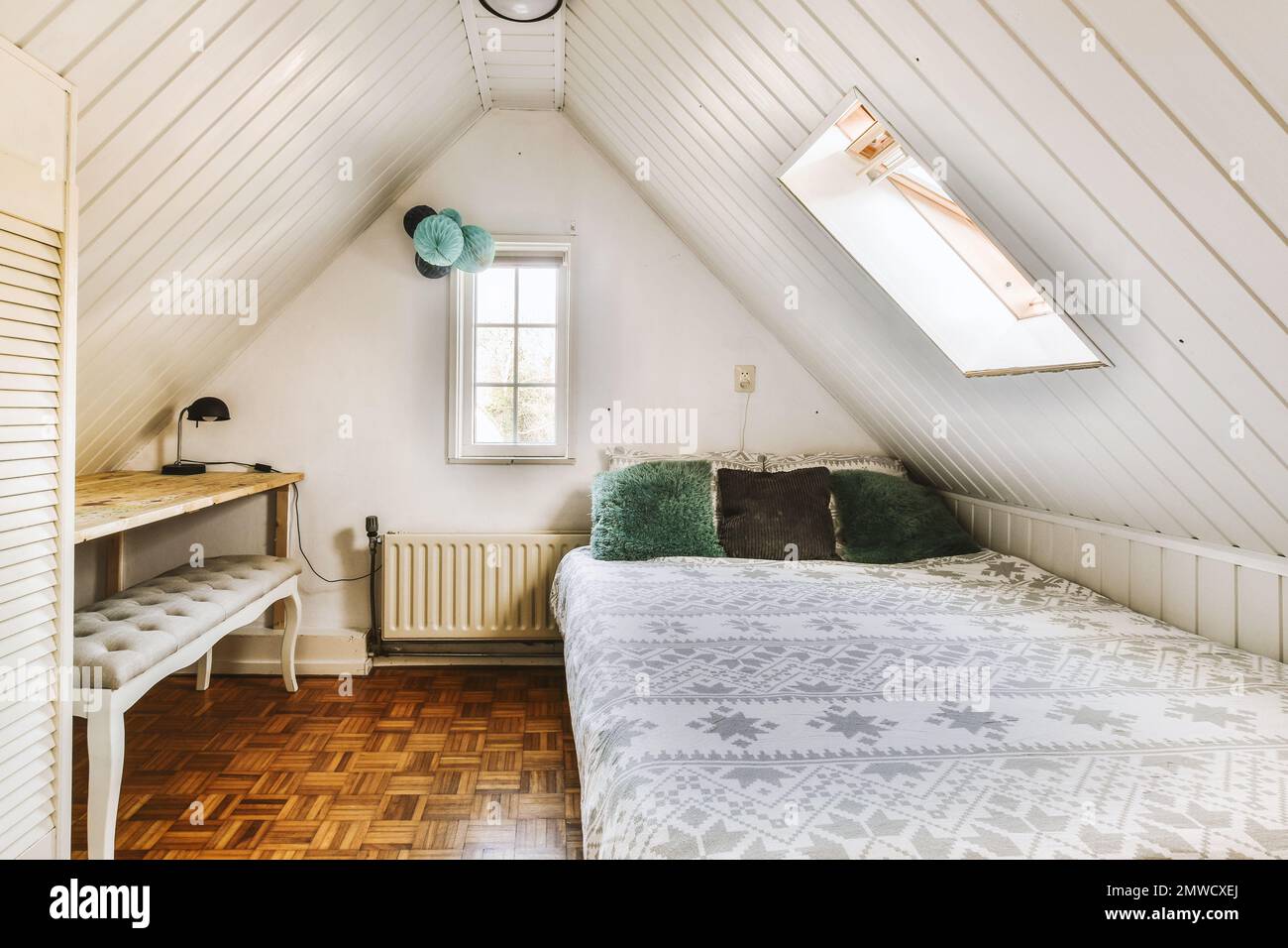 a bedroom with a bed, desk and window in the attic style dormer's loft