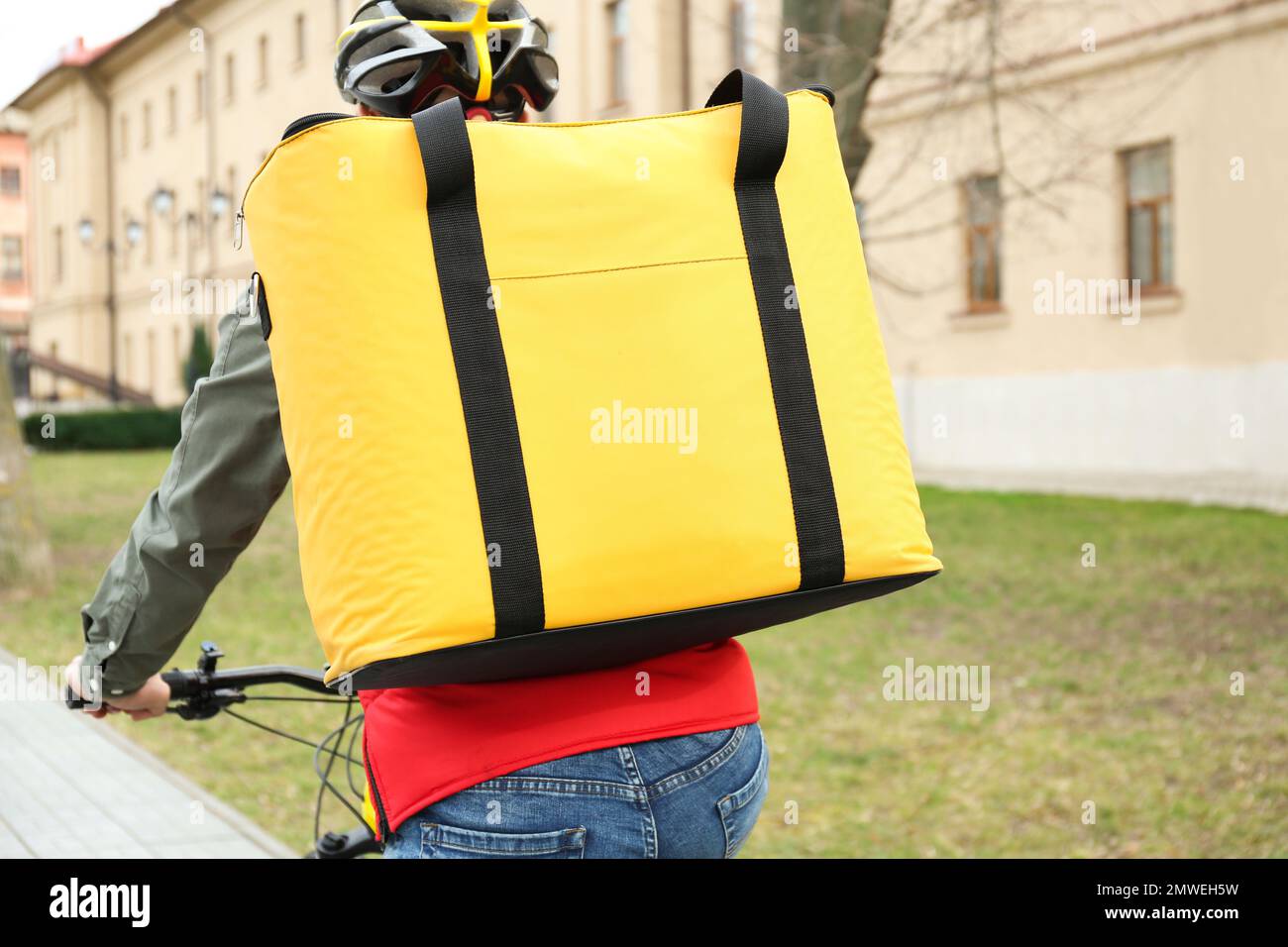 Courier with thermo bag riding bicycle outdoors. Food delivery service