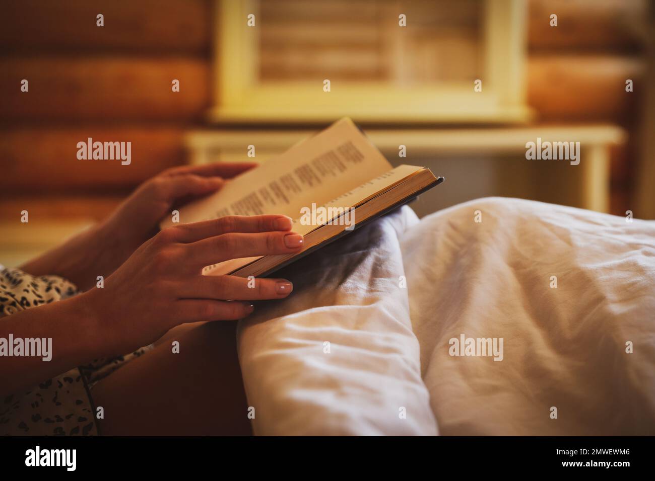 Woman reading book in bed at home, closeup Stock Photo