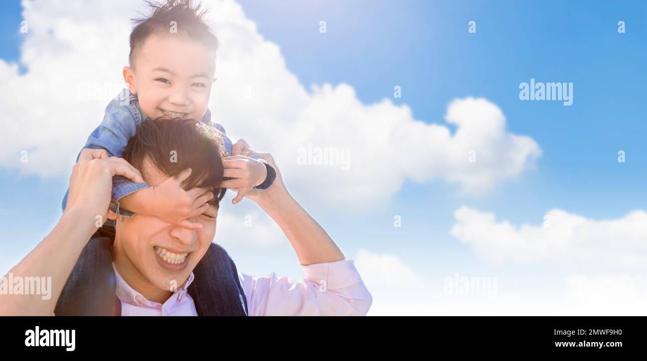 Happy father carrying little boy on back and playing at the park Stock Photo