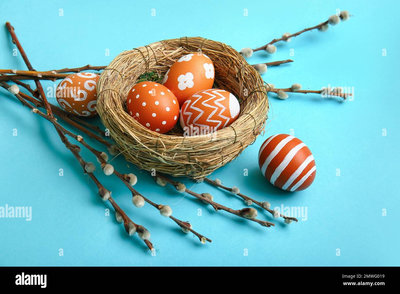 Nest with beautiful Easter eggs and willow branches on color background ...
