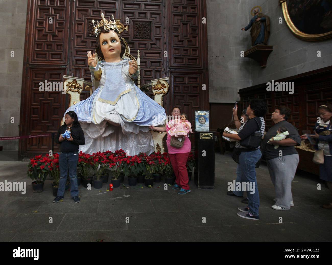 Faithful walk next to a giant baby Jesus statue inside the Metropolitan Cathedral in Mexico City