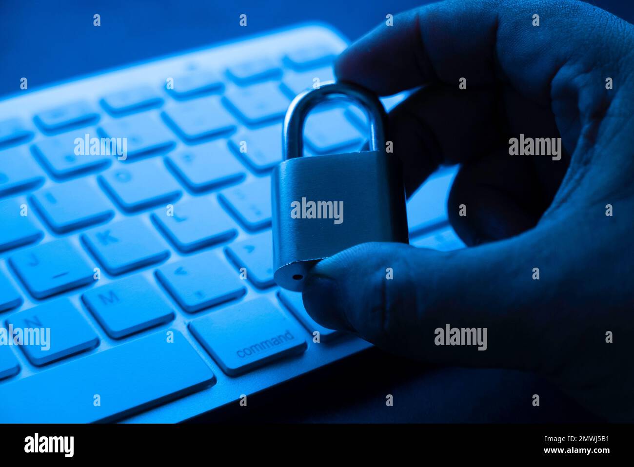 Computer security concept. Hand holding padlock on laptop keyboard.Computer is protected from online cybercrime and hacking Stock Photo