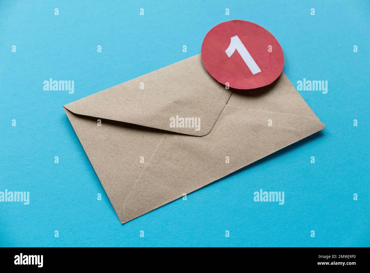 Concept of new email reminder or message alert. Brown craft envelope with a red symbol of notification on a blue background. Stock Photo