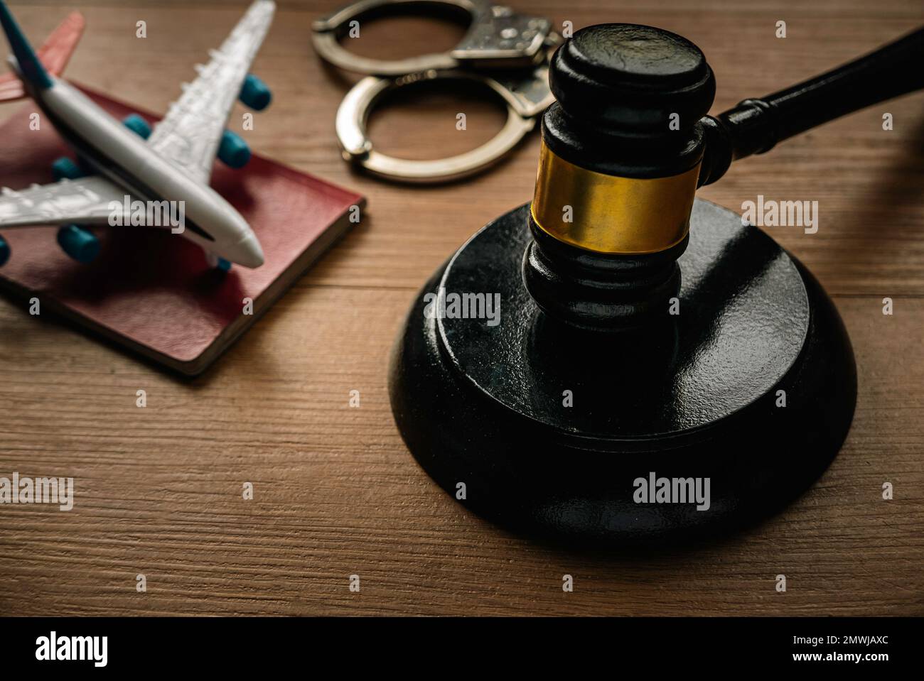 Concept of aviation law,international law, immigration law and citizenship rights. Gavel, passport, hand cuff and toy plane on a wooden background. Stock Photo