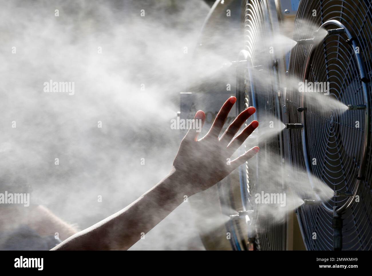 Spectator Hand Roster Fan A spectator holds a hand up in front of a cooling fan spraying water at ...
