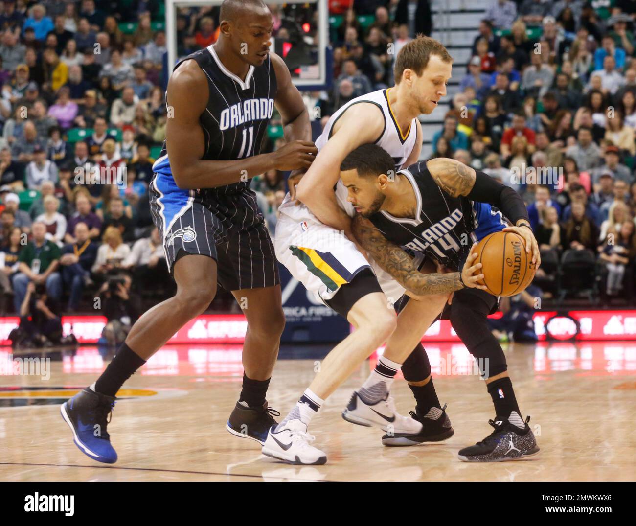 Orlando Magic's D.J. Augustin (14) looks for an opening past Utah Jazz's  Joe Ingles, middle, as Magic's Bismack Biyombo stands near Ingles during  the first half of an NBA basketball game Saturday
