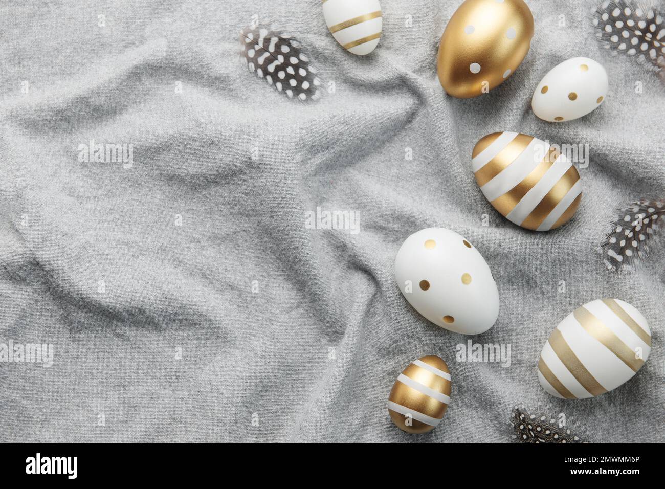 Easter eggs are painted with gold paint on a gray linen background ...