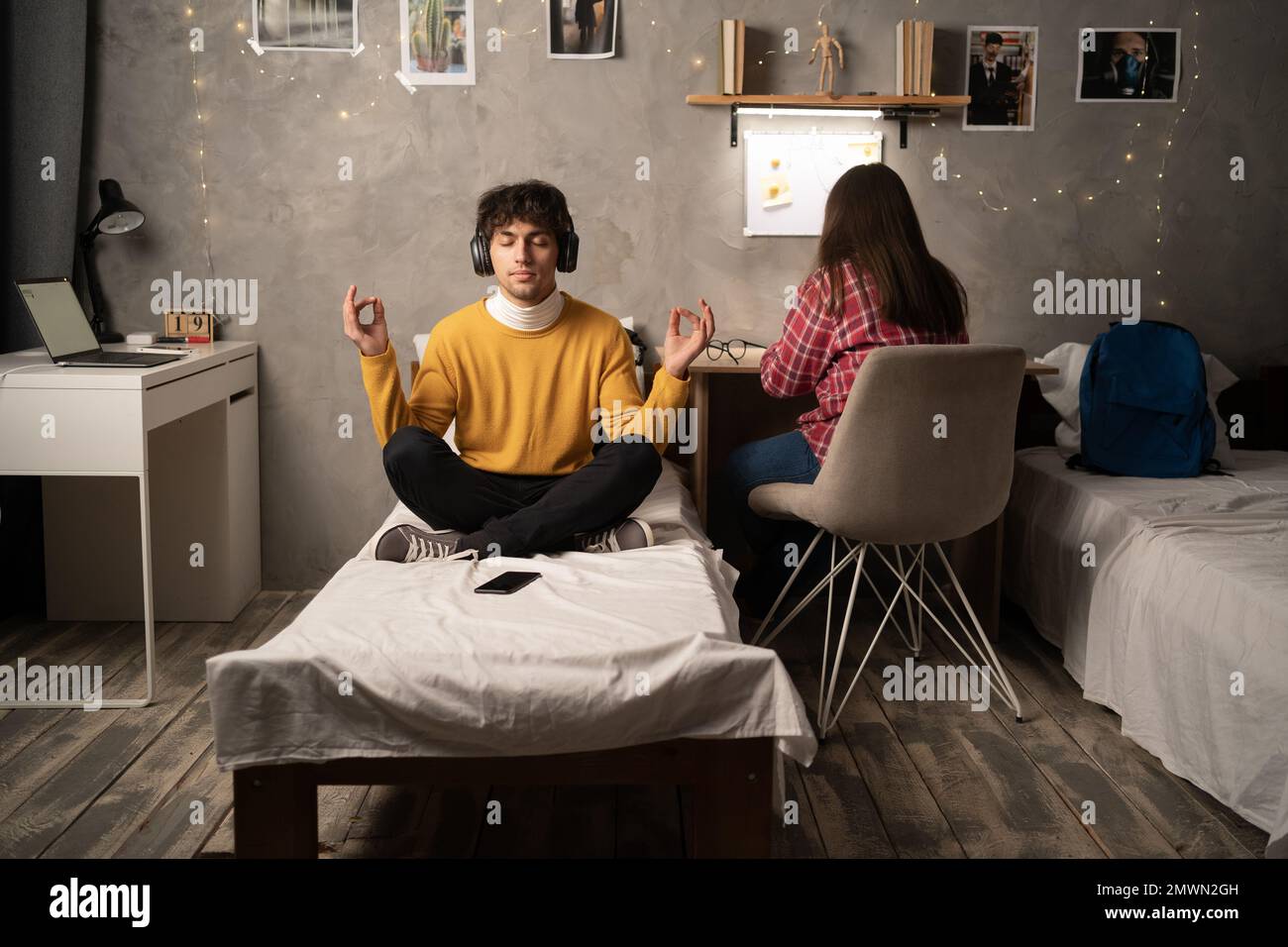 Student meditating on bed in college dorm room. Copy space Stock Photo