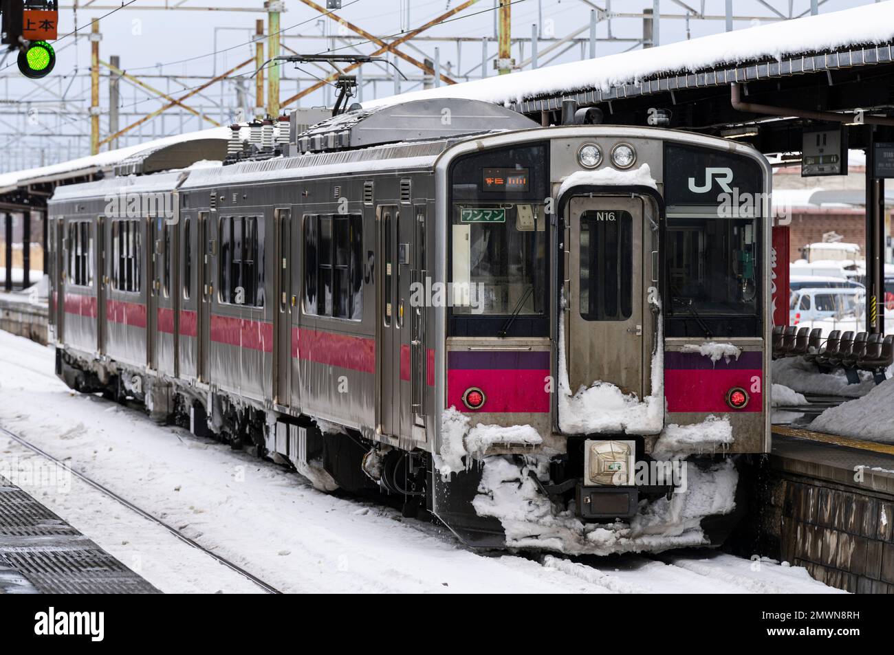 A JR East 701 Series local train at Tsuruoka Station in Yamagata Prefecture on a snowy day. Stock Photo