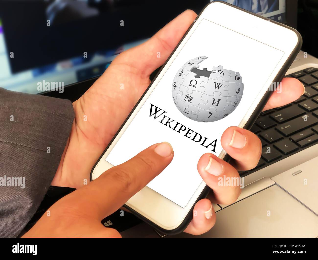 29.1, Pakistan. Wikipedia editorial background man touching the mobile screen and laptop in the backdrop Stock Photo