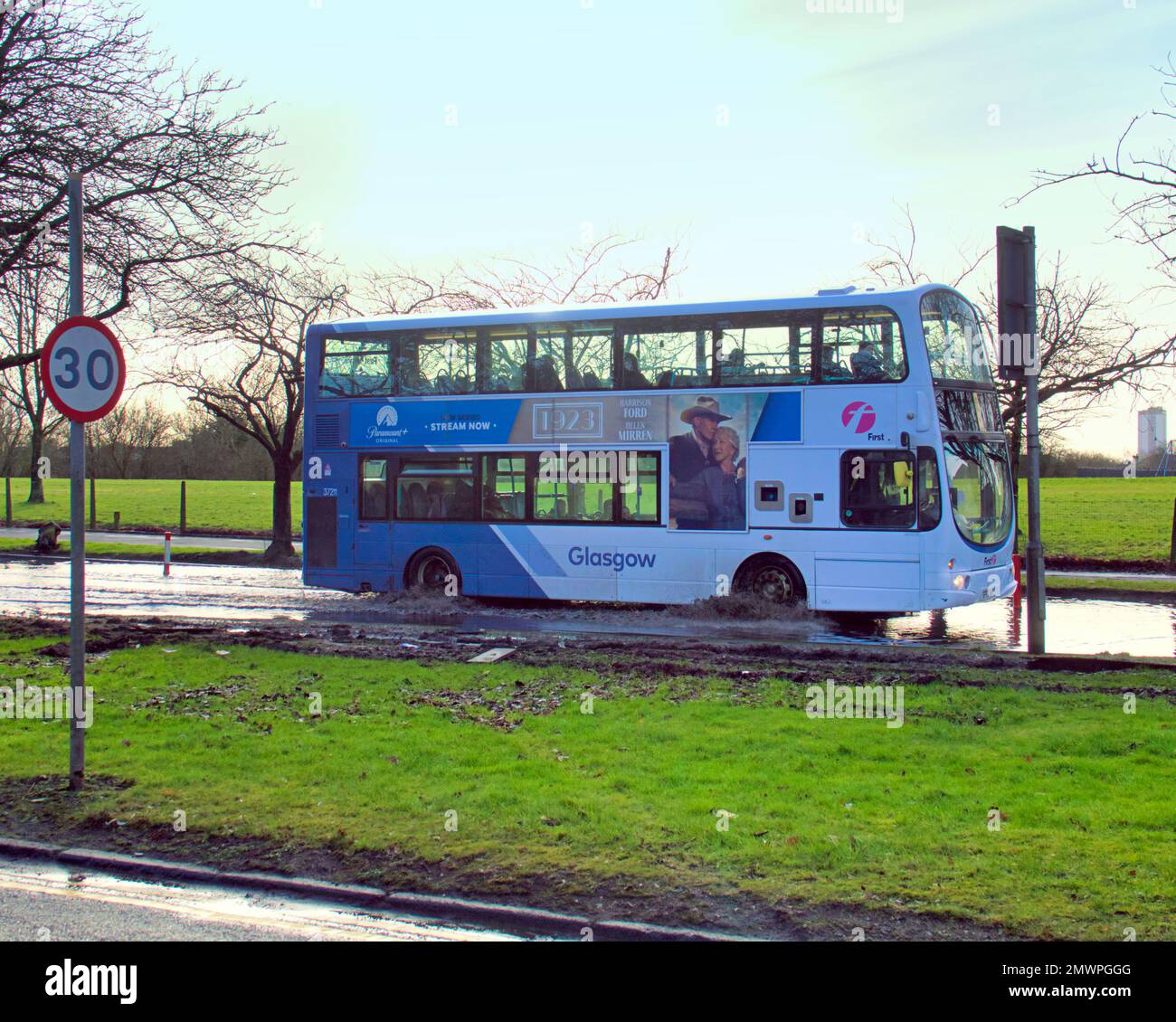 A first bus makes its way through flood water on great western road A82 Stock Photo