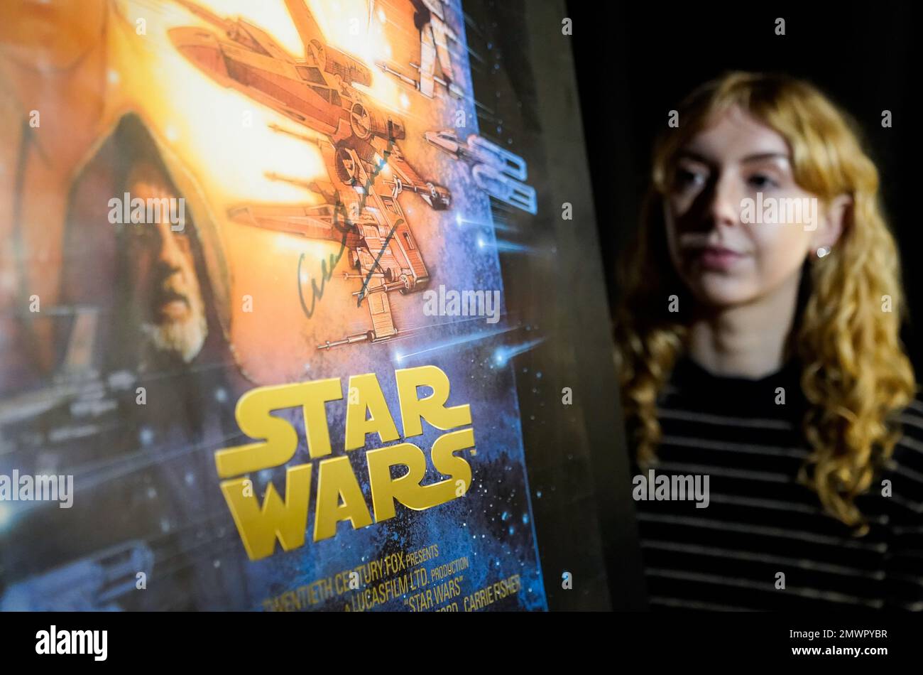 A Propstore employee looks at one of a set of three Sir Alec Guinness autographed posters for the Star Wars Special Edition Trilogy (1997) (Estimate £3000 - £6000) during a preview for the showbiz memorabilia auction, at the Propstore in Rickmansworth, Hertfordshire. Picture date: Thursday January 19, 2023. Stock Photo