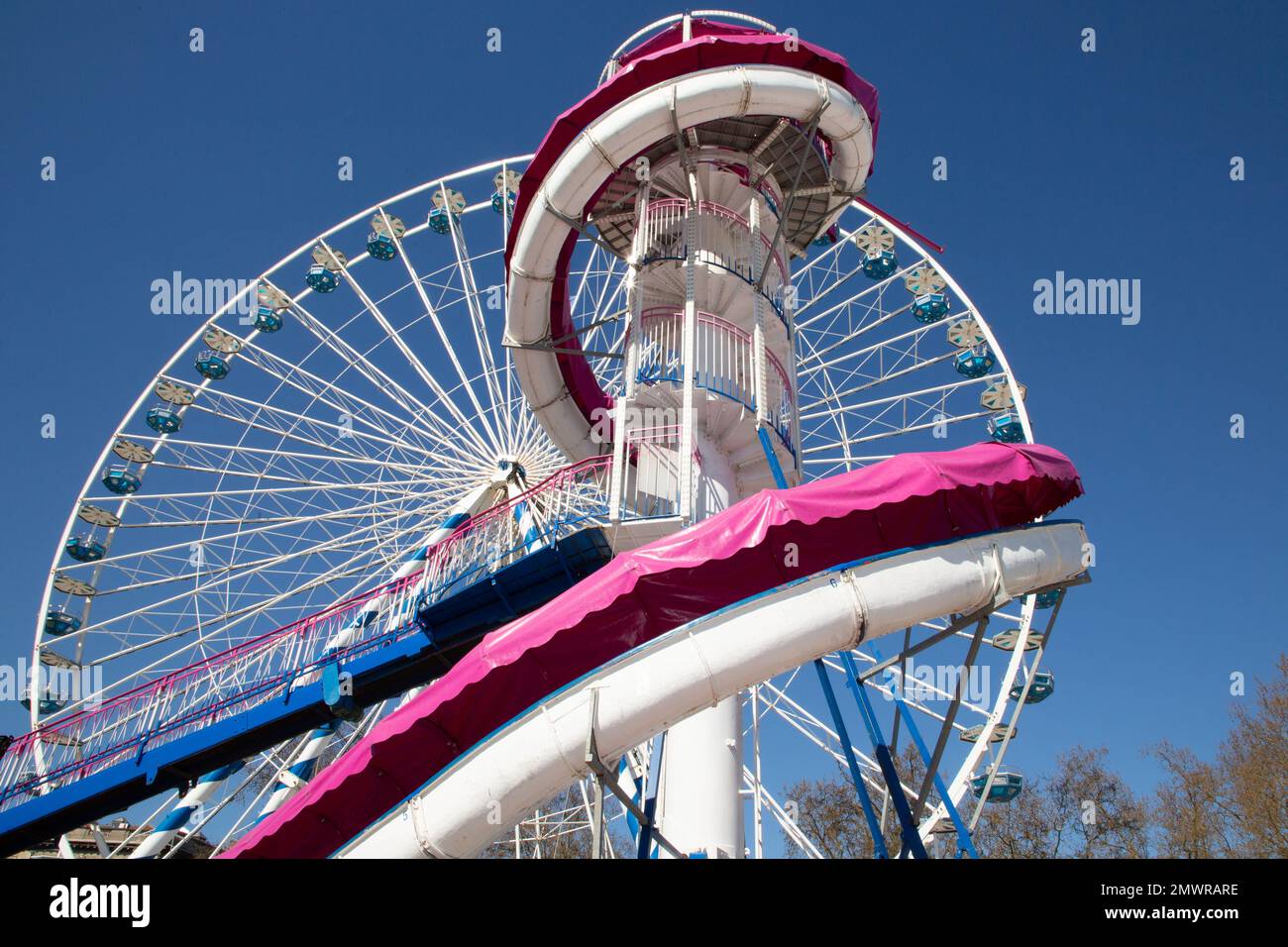 colorful Ferris wheel against a clear blue sky big wheel carousel with white pink giant slide Stock Photo