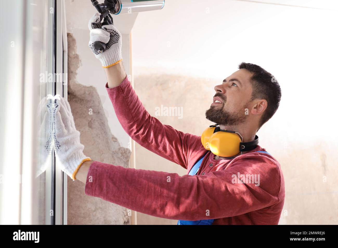 Worker using foam gun for window installation indoors Stock Photo Alamy