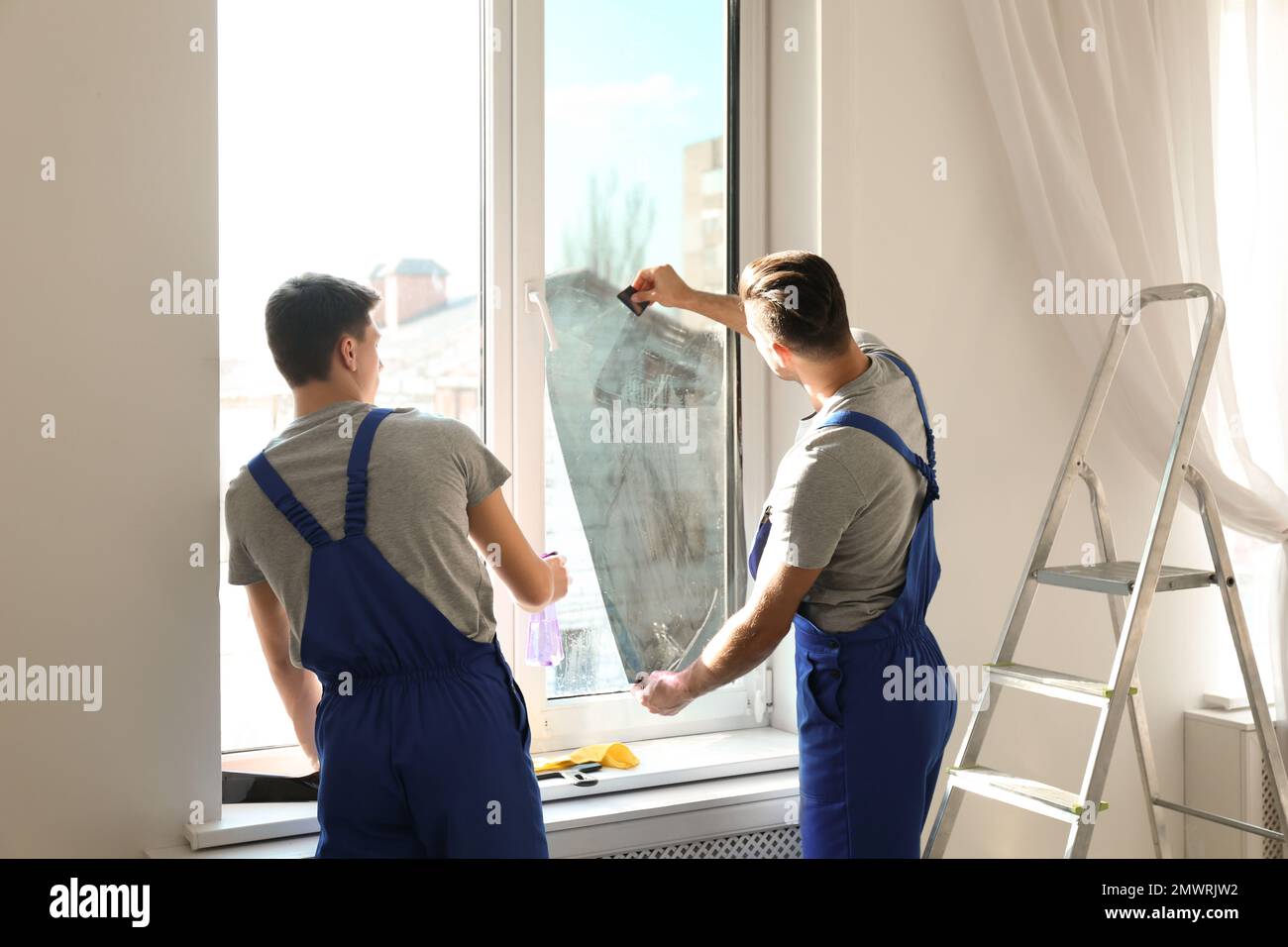 Professional workers tinting window with foil indoors Stock Photo
