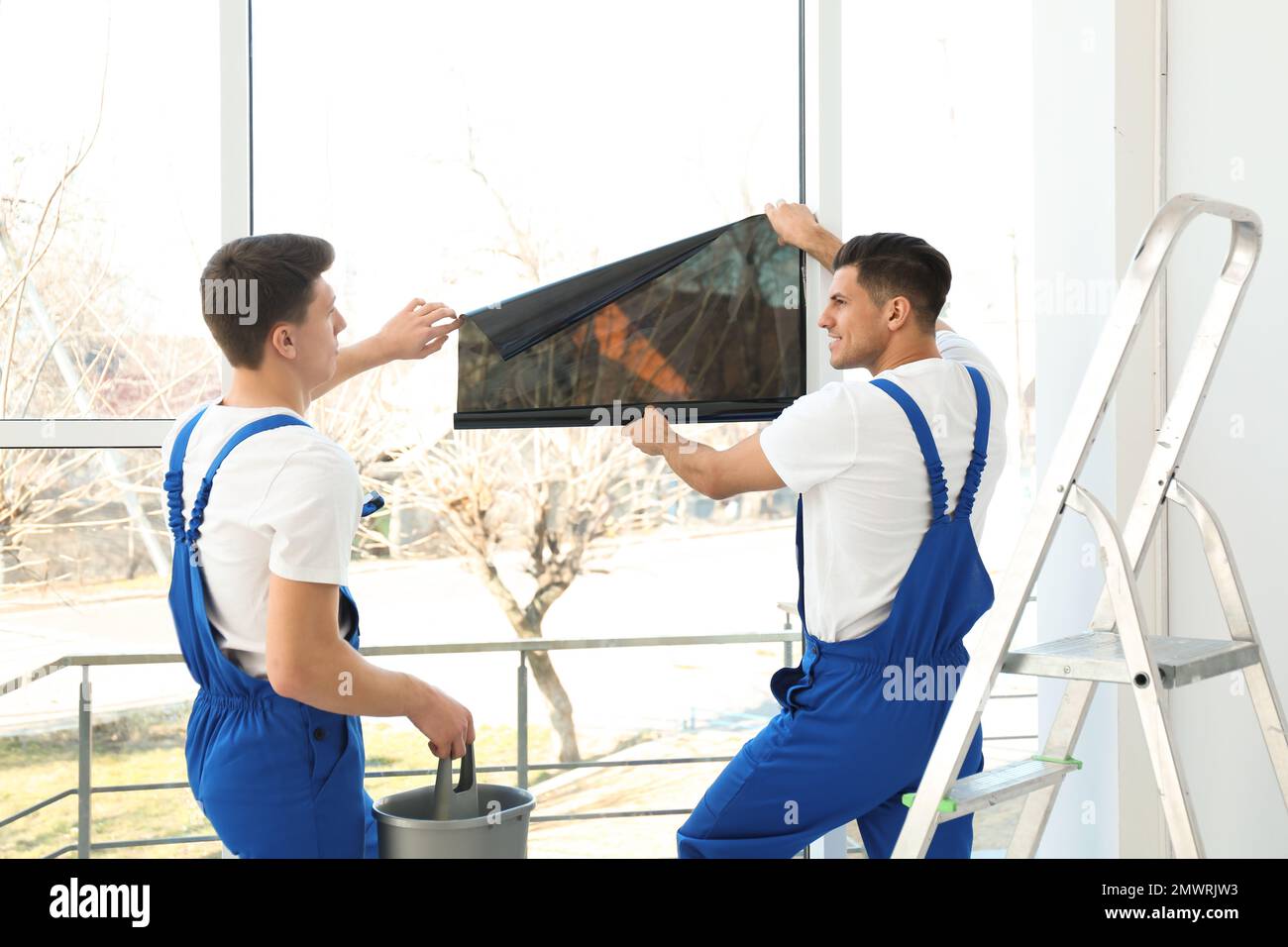 Professional workers tinting window with foil indoors Stock Photo