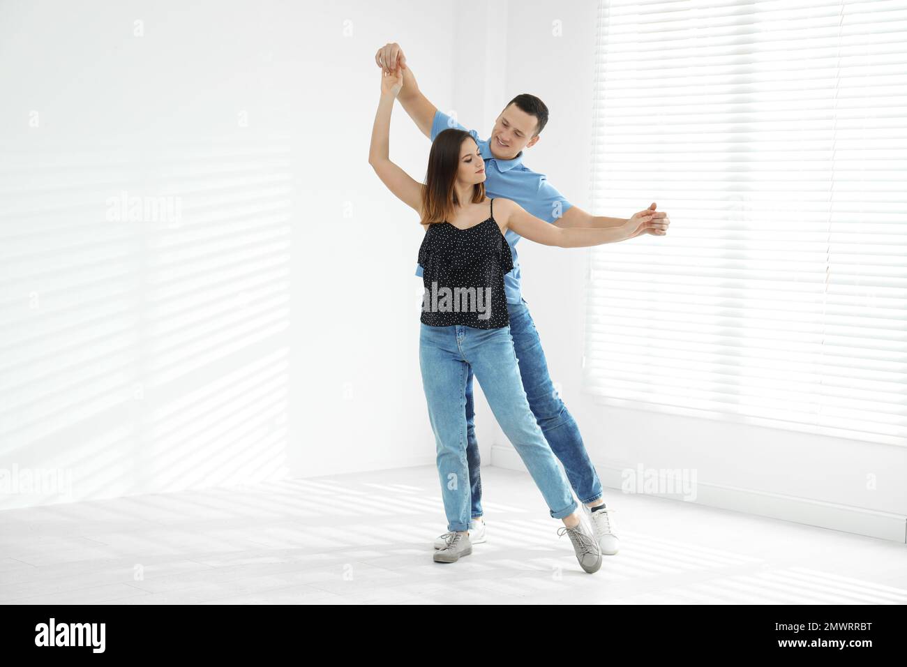 Beautiful young couple dancing in empty studio Stock Photo - Alamy