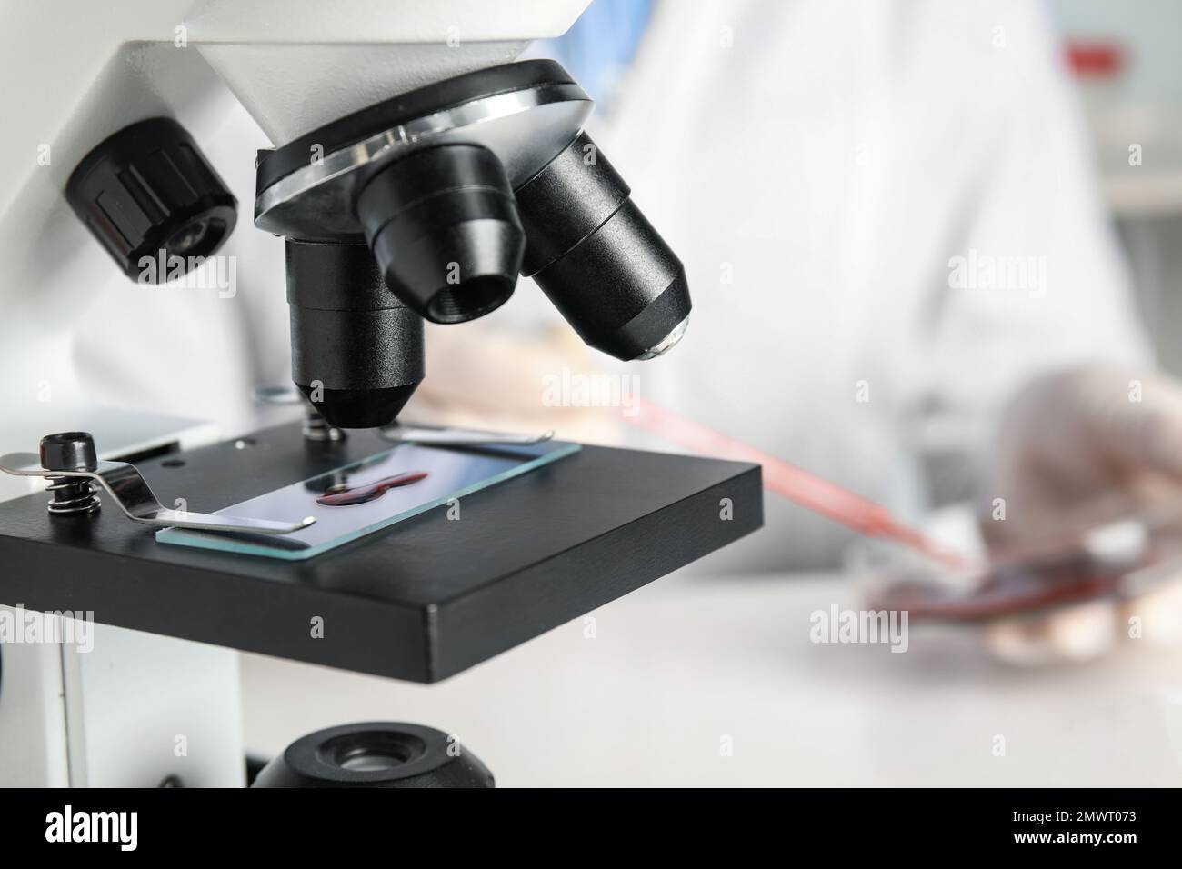 Slide with blood sample on microscope in laboratory, closeup. Virus