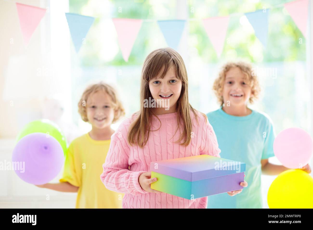 Kids birthday party. Child blowing out candles on colorful cake. Little