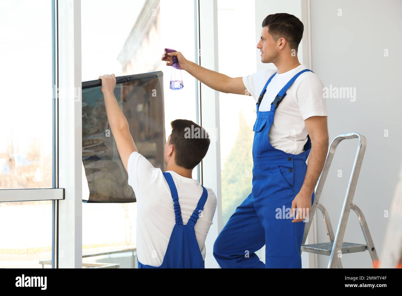 Professional workers tinting window with foil indoors Stock Photo