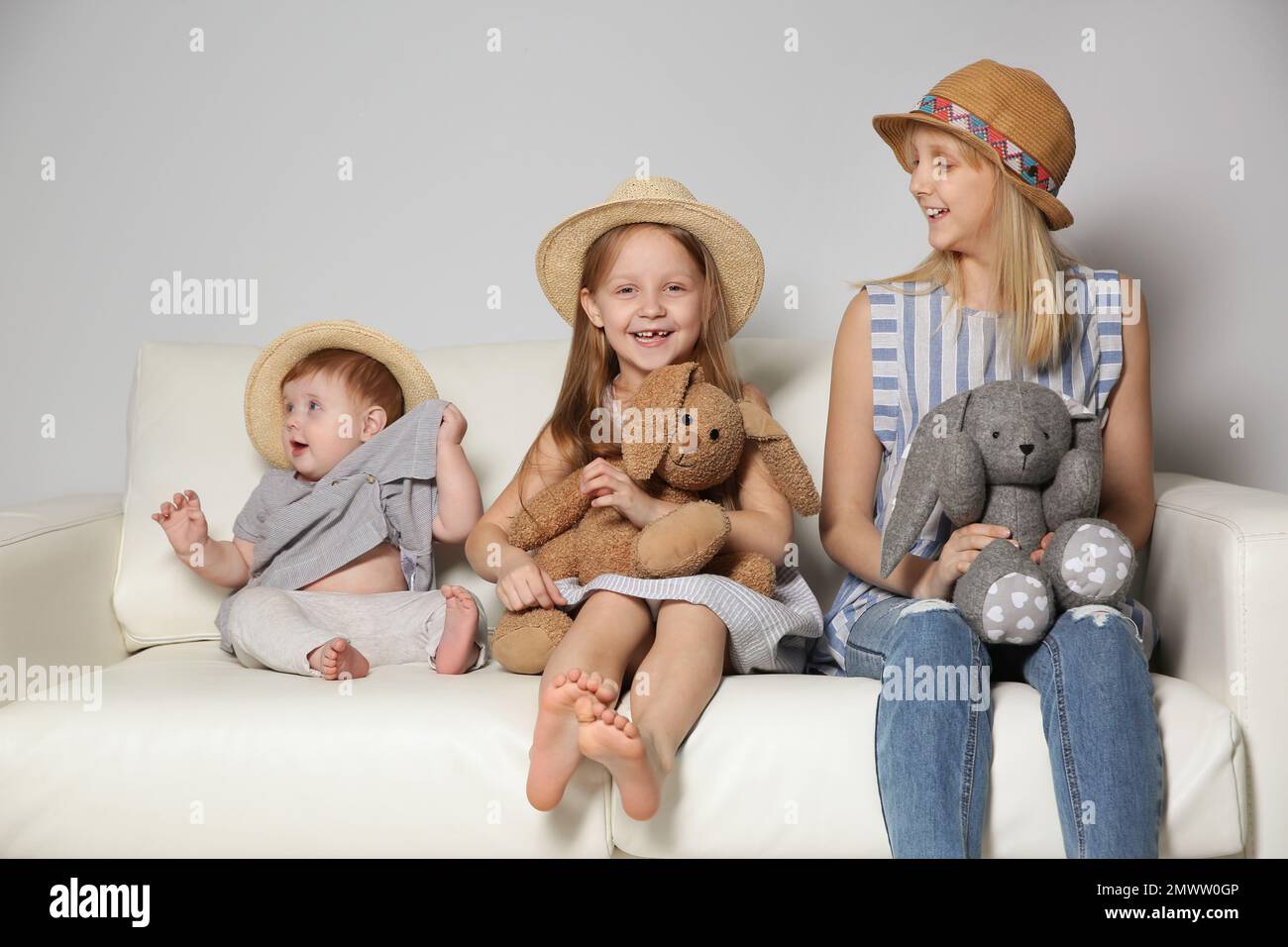 Happy children wearing hats on sofa at home Stock Photo - Alamy