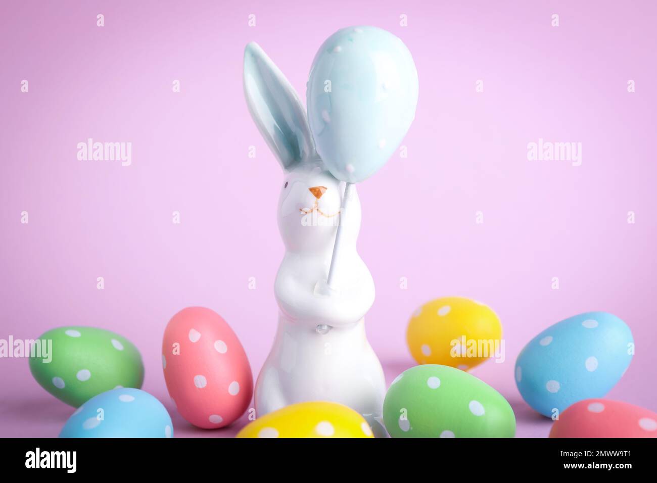 Easter bunny figure and dyed eggs on violet background Stock Photo