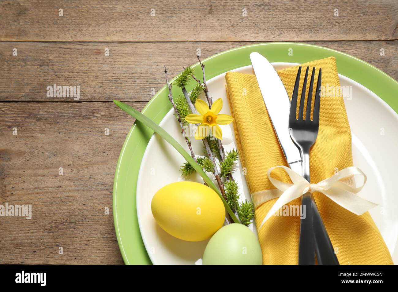 Festive Easter table setting with beautiful narcissus and painted eggs, top view Stock Photo