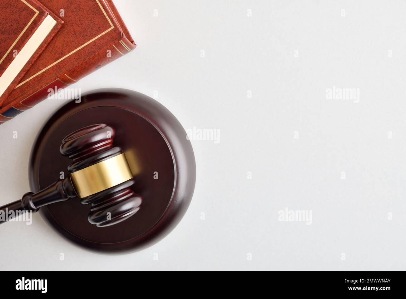 Background with wooden gavel and stacked law books isolated on wite table. Top view Stock Photo