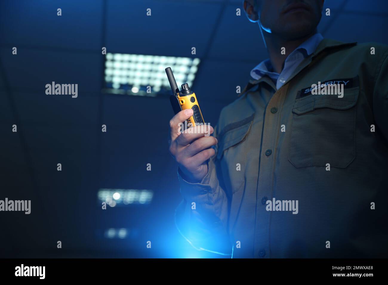 Professional security guard with portable radio set in dark room ...