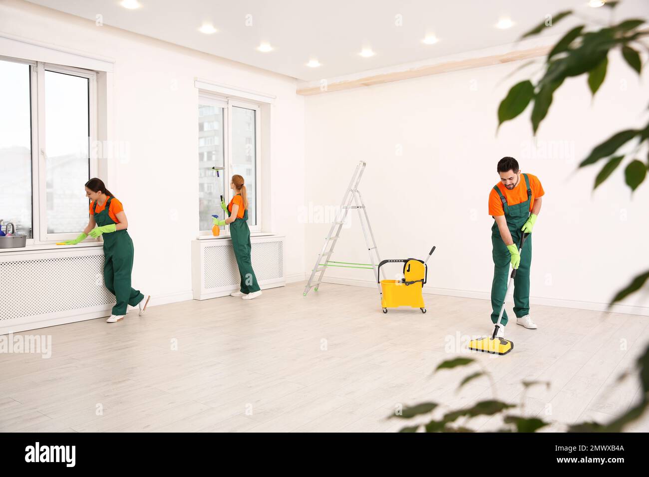 Team of professional janitors in uniforms cleaning room Stock Photo