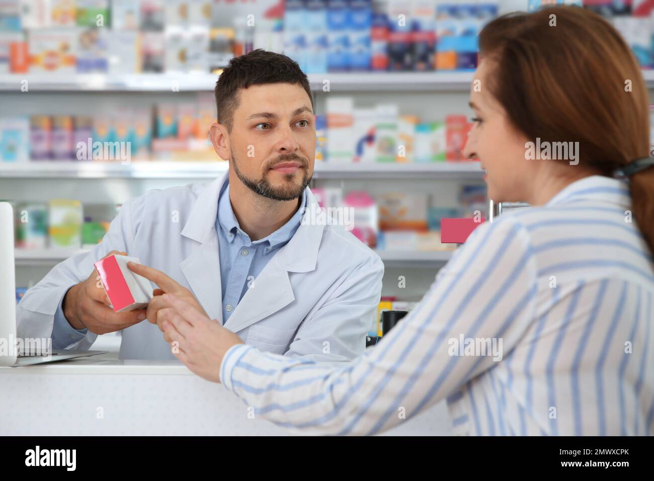 Professional pharmacist giving medicine to customer in drugstore Stock