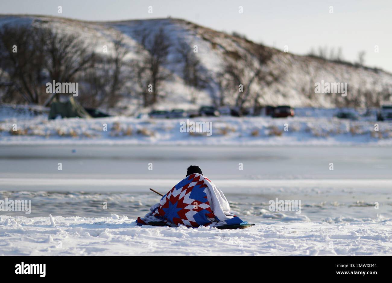 A man sits along the Cannonball river at the Oceti Sakowin camp where